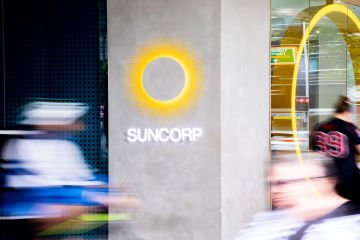 Blurred people walking past Suncorp logo