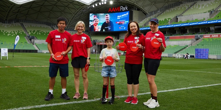 people in aami and what ability red tshirt standing inside football stadium holding red aami frisbees