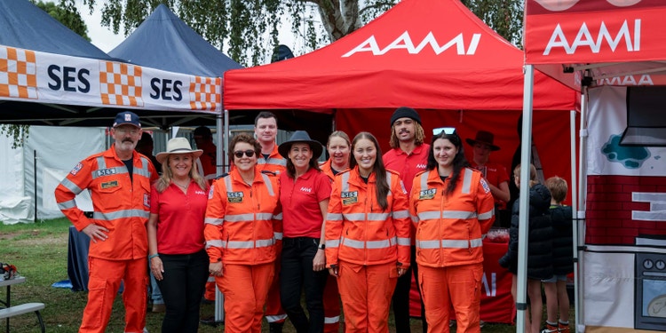 group of ses and aami volunteers wearing orange and red standing in front of marquee
