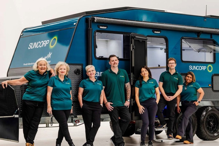 Two Suncorp employees sitting next to mobile hub speaking to customer sitting across white table