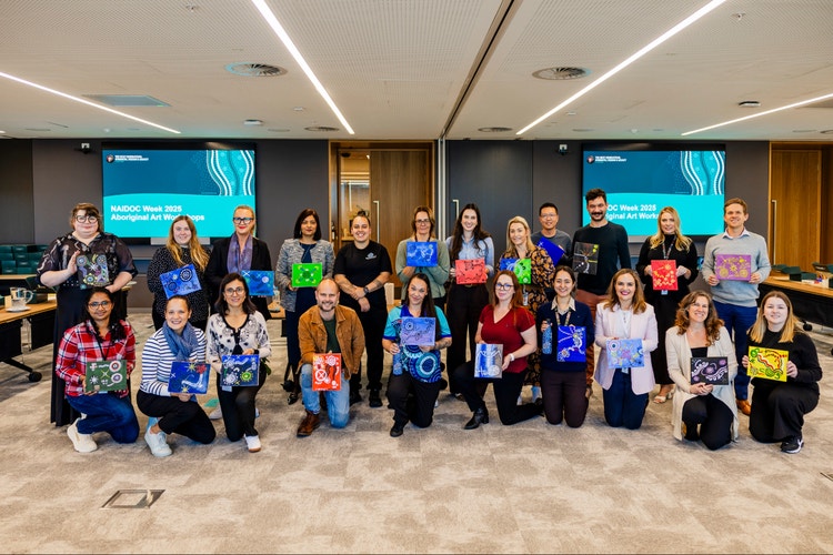 group photo of suncorp staff holding paintings for NAIDOC week