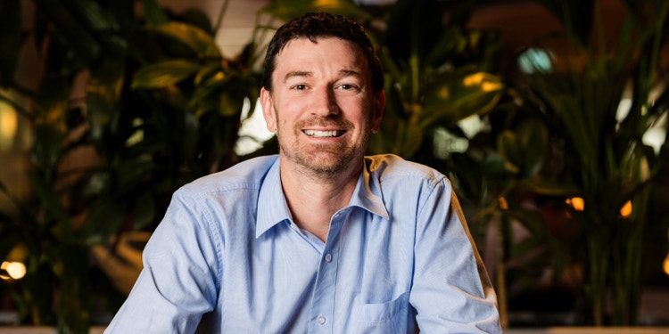 man wearing blue button up shirt sitting in front of plants