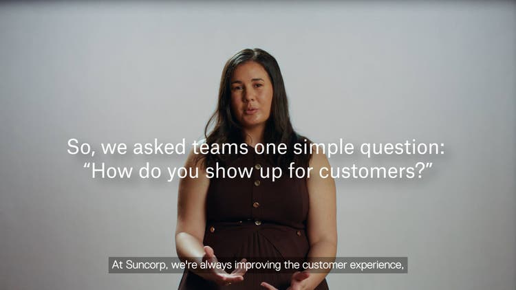 Woman wearing brown dress sitting and talking to camera.