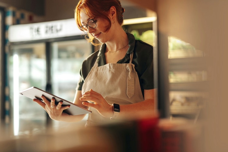 businesswoman wearing apron holding tablet standing in kitchen