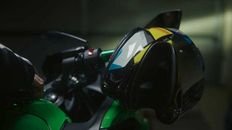 Green motorbike handle with helmet hanging on the side.