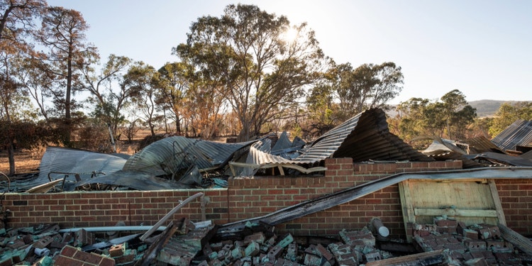 home devastated by fire with only walls remaining, with sunny background