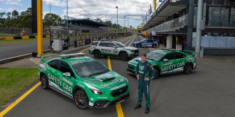green shannons brand safety and medical cars with man in shannons racing outfit standing on front of them on racing track