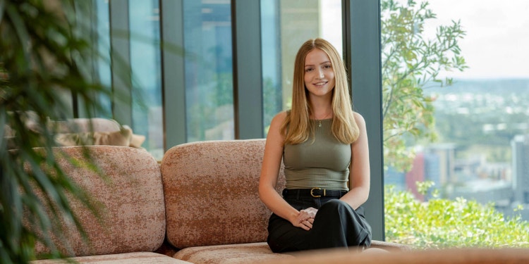 woman with blond hair sitting on brown couch next to large window