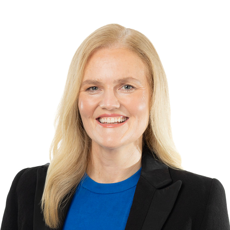 blond woman smiling wearing black blazer and blue dress