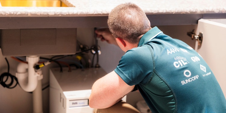 Suncorp assessor leaning under sink and checking flexi-hose