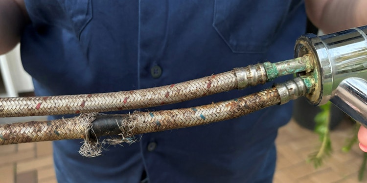 person holding corroded flexi-hose